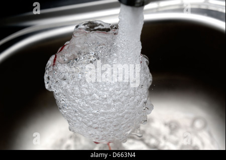 Un verre d'être rincé sous un robinet Banque D'Images