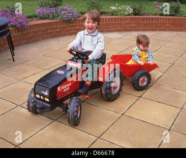 Les jeunes garçons jouant sur tracteur jouet, Suffolk, Angleterre, Royaume-Uni Banque D'Images