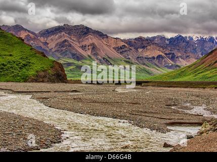 27 juin 2012 - L'Arrondissement de Denali, Alaska, États-Unis - nuages de tempête de recueillir plus de la vallée glaciaire de sculpté à la Toklat, l'un de la tresse de rivières à travers la forêt boréale et de la toundra du 6 million d'acres (24,500åÊkm) Parc National Denali et préserver. Chargé avec des débris de roche glaciaire et le ruissellement de la neige fondante, elles évoluent et s'entremêlent leurs chaînes sur la vallée et d' influence radicalement la topographie. Robuste, Multi-couleur de la montagnes polychromes de l'Alaska augmentation de la distance au-delà de l'Toklat River Bridge. (Crédit Image : © Arnold Drapkin/ZUMAPRESS.com) Banque D'Images