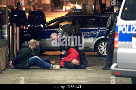 Un agent de police menottes un homme allongé sur le sol à Brême, Allemagne, 12 avril 2013. Une lutte entre les gens avec un fond de musique rock a provoqué une opération d'envergure pour la police : environ 40 membres du groupe moto 'Hell's Angels' et 'Mongols' avec lui dans le centre-ville de Bremen. Photo : Florian Kater Banque D'Images