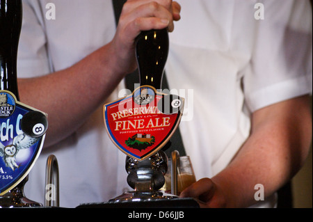 Un barman pulling a pint of Castle Rock Brewery, Nottingham "Préservation Fine Ale' à partir d'une pompe à main Banque D'Images