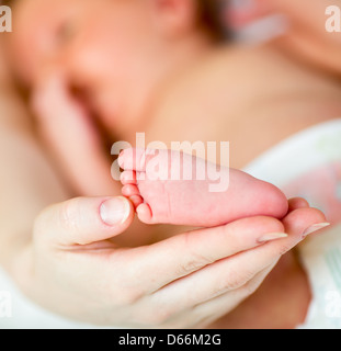 Mother's hand holding small baby's foot Banque D'Images