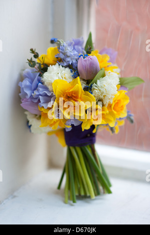 Mariage bouquet de fleurs de printemps, la jonquille y compris pois doux, tulip en jaune, bleu, rose et violet par une fenêtre Banque D'Images