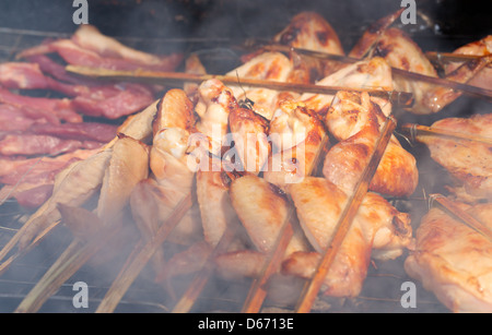 Ailes de poulet délicieux sur le barbecue dans la fumée de cuisson barbecue Banque D'Images