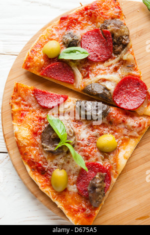Deux grandes tranches de pizza au fromage, salami et champignons à bord, vue d'en haut Banque D'Images
