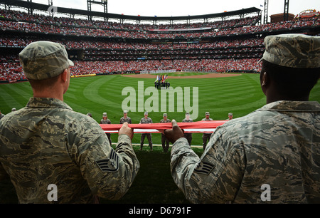 Les aviateurs de la 375th Air Mobility Wing, Scott Air Force base, Illinois, déploient un grand drapeau américain pour 50 000 fans lors de la journée d'ouverture au Busch Stadium, fait Louis. L'événement marque leur première présentation du drapeau lors d'un match de baseball. Banque D'Images