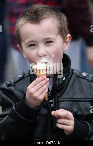 Un jeune homme dans une veste en cuir sur la photo de manger une glace sur une journée ensoleillée à Preston Park, Brighton, East Sussex, UK. Banque D'Images