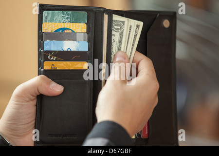 La main de l'homme pour obtenir de l'argent à partir de la sac à main noir Banque D'Images