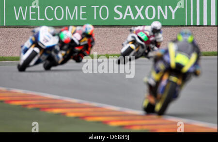 Les pilotes MotoGP passe devant une 'Bienvenue à la Saxe' banner lors de la formation pour le Grand Prix d'Allemagne sur le champ de courses au Sachsenring à Hohenstein-Ernstthal, Allemagne, 07 juillet 2012. Photo : JAN WOITAS Banque D'Images