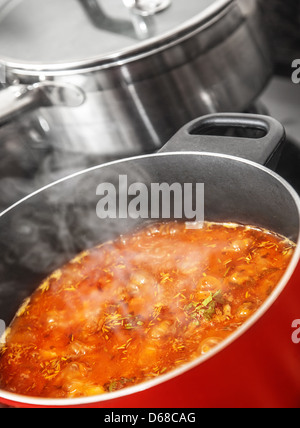 Gros plan du rouge savoureux le bortsch ukrainien d'ébullition dans la casserole sur la cuisinière, des plats délicieux et sains de la soupe aux tomates Banque D'Images