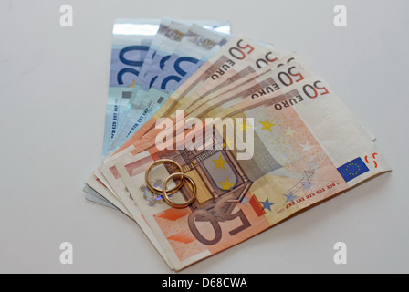 L'argent et les billets en euros avec deux anneaux de mariage en or sont au-dessus de la pile Banque D'Images