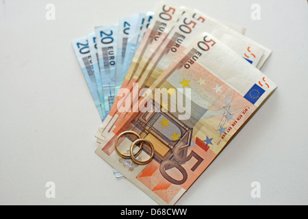 L'argent et les billets en euros avec deux anneaux de mariage en or sont au-dessus de la pile Banque D'Images