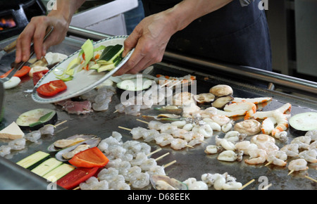 Chef chinois alors qu'il fait cuire des légumes et de la viande de poisson dans la plaque Banque D'Images