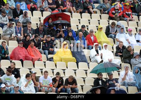 Les spectateurs à la tribune se protéger avec parasols et la pluie couvre au cours de la deuxième session d'essais au champ de courses d'Hockenheim à Hockenheim, Allemagne, 20 juillet 2012. Le Grand Prix de Formule 1 d'Allemagne aura lieu le 22 juillet 2012. Photo : David Ebener dpa  + + +(c) afp - Bildfunk + + + Banque D'Images