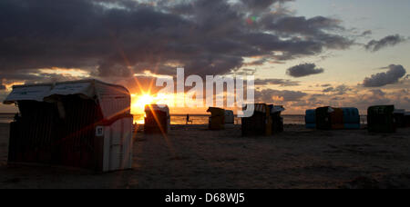 Chaises de plage en osier sont à la plage tandis que le soleil se couche à l'arrière-plan sur la mer des wadden à Norddeich, Allemagne, 22 juillet 2012. Les météorologues prévoient des températures plus élevées et plus de soleil pour les prochains jours. Photo : Sven Hoppe Banque D'Images