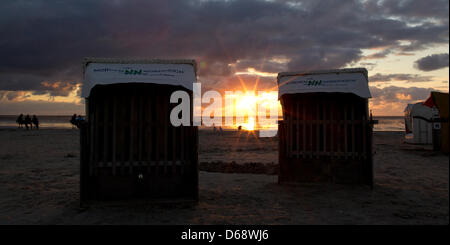 Chaises de plage en osier sont à la plage tandis que le soleil se couche à l'arrière-plan sur la mer des wadden à Norddeich, Allemagne, 22 juillet 2012. Les météorologues prévoient des températures plus élevées et plus de soleil pour les prochains jours. Photo : Sven Hoppe Banque D'Images