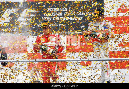 Le gagnant, pilote de Formule 1 espagnol Fernando Alonso de Ferrari (L), célèbre avec thirdplaced British Jenson Button de McLaren Mercedes sur le podium après avoir remporté le Grand Prix de Formule 1 de l'Allemagne à la piste de course d'Hockenheim à Hockenheim, Allemagne, 22 juillet 2012. Photo : Jens Buettner Banque D'Images