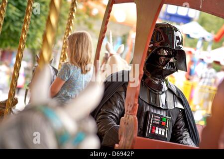 Une personne habillé comme Dark Vador est assis dans un manège au parc d'attractions Freizeitland Geiselwind Geiselwind, en Allemagne, le 28 juillet 2012. Les membres des clubs de fan de Star Wars à partir de l'ensemble de l'Allemagne apparaît en caractères de la série de films lors d'un défilé au parc d'attractions. Photo : David Ebener Banque D'Images