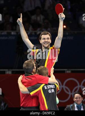 Le joueur de tennis de table Timo Boll (haut) célèbre avec son coéquipier Bastian Steger (R) et l'entraîneur Joerg Rosskopf (L) après avoir remporté la médaille de bronze chez les hommes team match contre Hong Kong dans ExCeL Arena au les Jeux Olympiques de 2012 à Londres, Londres, Grande-Bretagne, 08 août 2012. Photo : Friso Gentsch dpa. Photo : Friso Gentsch dpa  + + +(c) afp - Bildfunk + + + Banque D'Images