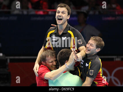 Le joueur de tennis de table Timo Boll (haut) célèbre avec ses coéquipiers Bastian Steger (R), Dimitrij Ovtcharov (C) et l'entraîneur Joerg Rosskopf (L) après avoir remporté la médaille de bronze chez les hommes team match contre Hong Kong dans ExCeL Arena au les Jeux Olympiques de 2012 à Londres, Londres, Grande-Bretagne, 08 août 2012. Photo : Friso Gentsch dpa. Photo : Friso Gentsch dpa  + + +(c) afp - Bildfunk + + + Banque D'Images