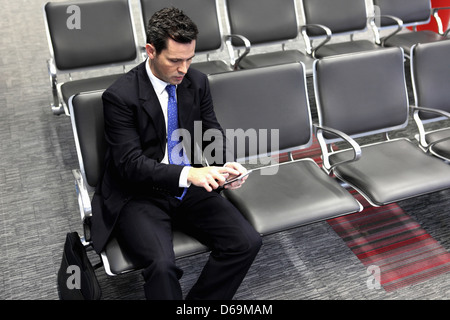 Businessman using cell phone in airport Banque D'Images