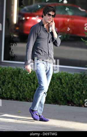 Brandon Davis fumeurs et de parler sur son téléphone cellulaire à Beverly Hills, Los Angeles, Californie Banque D'Images