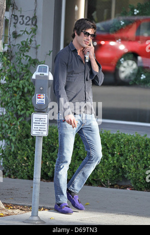 Brandon Davis fumeurs et de parler sur son téléphone cellulaire à Beverly Hills, Los Angeles, Californie Banque D'Images
