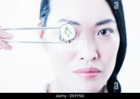 Woman holding morceau de sushi sur eye Banque D'Images