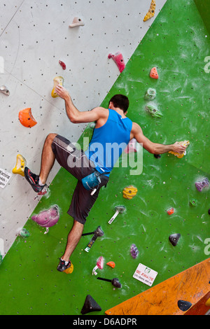 Fit man bouldering sur un mur d'escalade. Banque D'Images