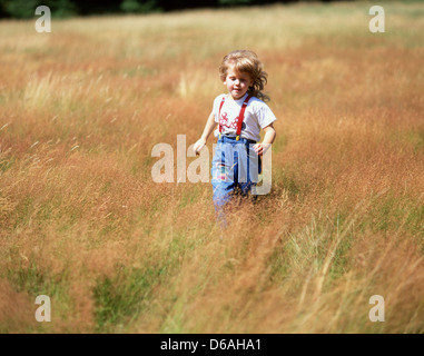 Jeune fille courir à travers les champs, Sunninghill, Berkshire, Angleterre, Royaume-Uni Banque D'Images