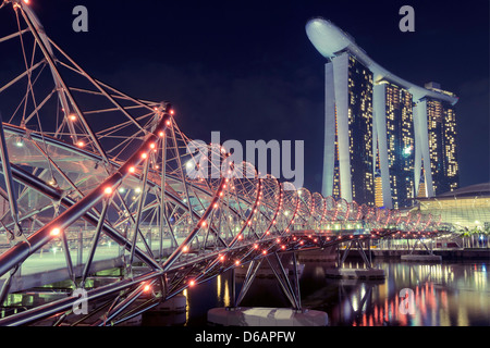 Pont piéton Helix à Singapour avec l'éclairage de nuit panoramique et Marina Bay Sands hotel sur arrière-plan. Banque D'Images