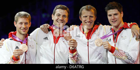 Allemagne (L-R) Bastian Steger, Timo Boll, entraîneur Joerg Rosskopf et Dimitrij Ovtcharov célébrer leurs médailles de bronze lors de la cérémonie de remise des médailles pour l'équipe masculine de tennis de table dans ExCeL à l'arène pour les Jeux Olympiques de 2012 à Londres, Londres, Grande-Bretagne, 08 août 2012. Photo : Friso Gentsch dpa  + + +(c) afp - Bildfunk + + + Banque D'Images