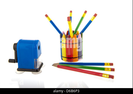 Un collage de couleurs crayons dans une tasse avec un taille-crayon bleu isolé sur fond blanc Banque D'Images