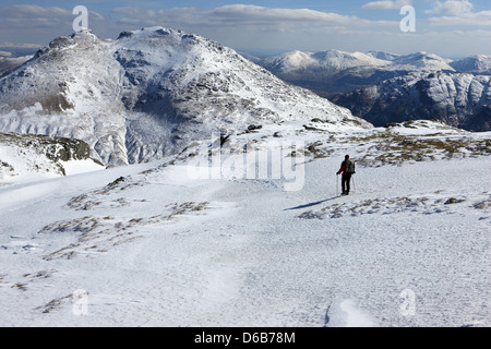 Hillwalker en ordre décroissant les pentes couvertes de neige de Beinn Luibhean (858m) avec le cordonnier aussi connu comme Ben Arthur (884m) de l'avant. Banque D'Images