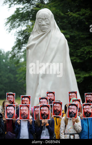 Les visiteurs de l'exposition d'art contemporain documenta assister à une action de protestation et contenir jusqu'portraits de l'artiste chinois Ai Weiwei devant leurs visages au ghost statue d'Apichatpong Weerasethakul à Kassel, Allemagne, 24 août 2012. Konceptual l'artiste Michael Werner est initiateur du projet "Alles fuer AiWeiwei (tout pour Ai Weiwei), qui comprend des actions de protestation avec masques s Banque D'Images