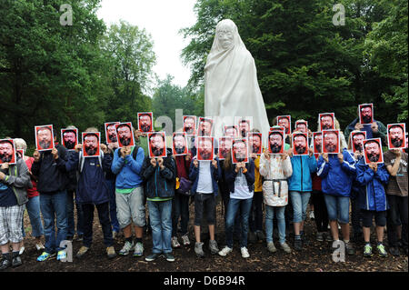 Les visiteurs de l'exposition d'art contemporain documenta assister à une action de protestation et contenir jusqu'portraits de l'artiste chinois Ai Weiwei devant leurs visages au ghost statue d'Apichatpong Weerasethakul à Kassel, Allemagne, 24 août 2012. Konceptual l'artiste Michael Werner est initiateur du projet "Alles fuer AiWeiwei (tout pour Ai Weiwei), qui comprend des actions de protestation avec masques s Banque D'Images