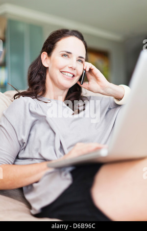 Woman on cell phone using laptop Banque D'Images