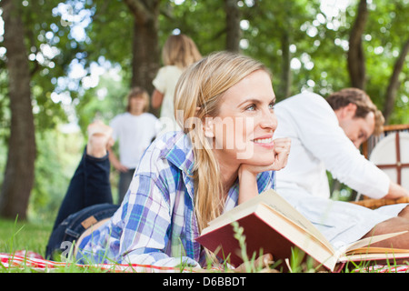 Woman reading on blanket in park Banque D'Images