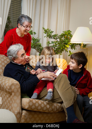 Vieux couple avec petits-enfants sur canapé Banque D'Images