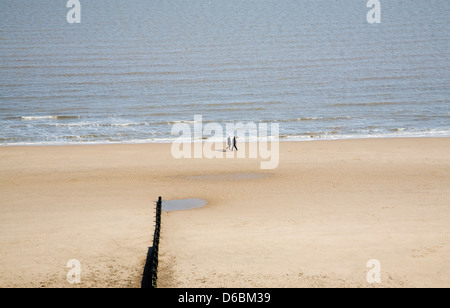 Les gens qui marchent sur une large plage de sable vide à Frinton and on Sea, Essex, Angleterre Banque D'Images