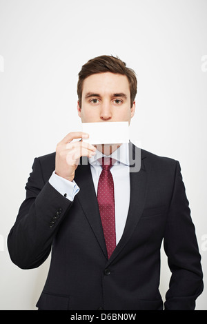 Businessman holding carte vierge sur son visage Banque D'Images