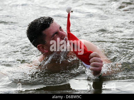 Un nageur ôte son chapeau de Noël au cours de la nouvelle année, la baignade dans le lac Edersee Hemfurth près, l'Allemagne, 01 janvier 2012. Le sixième jour de l'an nager a eu lieu près du barrage. Plus de 60 nageurs y la température de l'eau d'environ 5 degrés et un peu plus à l'aise à l'extérieur température de 12 degrés centigrades. Photo : Uwe Zucchi Banque D'Images