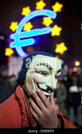 Un manifestant s'élève face à l'Euro la sculpture comme il assiste à un rassemblement à l'occuper en camp de Francfort/Main, Allemagne, 31 décembre 2011. Les protestataires ont été camping à Francfort depuis le 15 octobre 2011 pour manifester contre le pouvoir des banques. Photo : Frank Rumpenhorst Banque D'Images