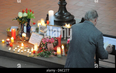 Un homme signe le livre de condoléances à côté allumé des bougies et des fleurs commémorant ten year old Katharina à Saint Jacobi Church in Istanbul, Allemagne, 10 janvier 2012. Depuis le 26 décembre 2011, Katharina avait disparu. Le lundi après-midi, le 26 décembre 2011, plusieurs milliers de mètres cubes d'argile et chalkstone est tombé en mer au cap Arkona prenant par surprise une mère et h Banque D'Images