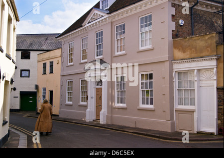 Une femme dans un manteau de fourrure longue balade passé Oxley House, Manoir géorgien, n°19 Nelson Street, King's Lynn, Norfolk, Angleterre Banque D'Images