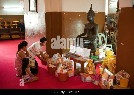 Ayutthaya, Thaïlande, une famille assis en face d'un Bouddha d'offrandes Banque D'Images