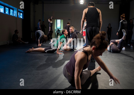 Un groupe d'hommes et de femmes acteurs masculins et féminins artistes danseurs réchauffe à SITI Méthode Suzuki de l'acteur atelier de formation classe, UK Banque D'Images