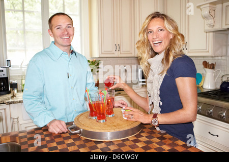 La femme et l'homme de faire des cocktails à l'intérieur de cuisine Banque D'Images