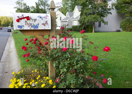 Boîte aux lettres dans un lit de fleur dans un quartier de banlieue. Banque D'Images