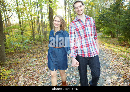 Fille et garçon tenant la main et marchant dans l'automne country road Banque D'Images